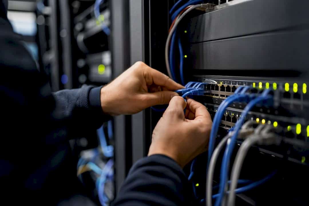 Hands managing network cables in a data center