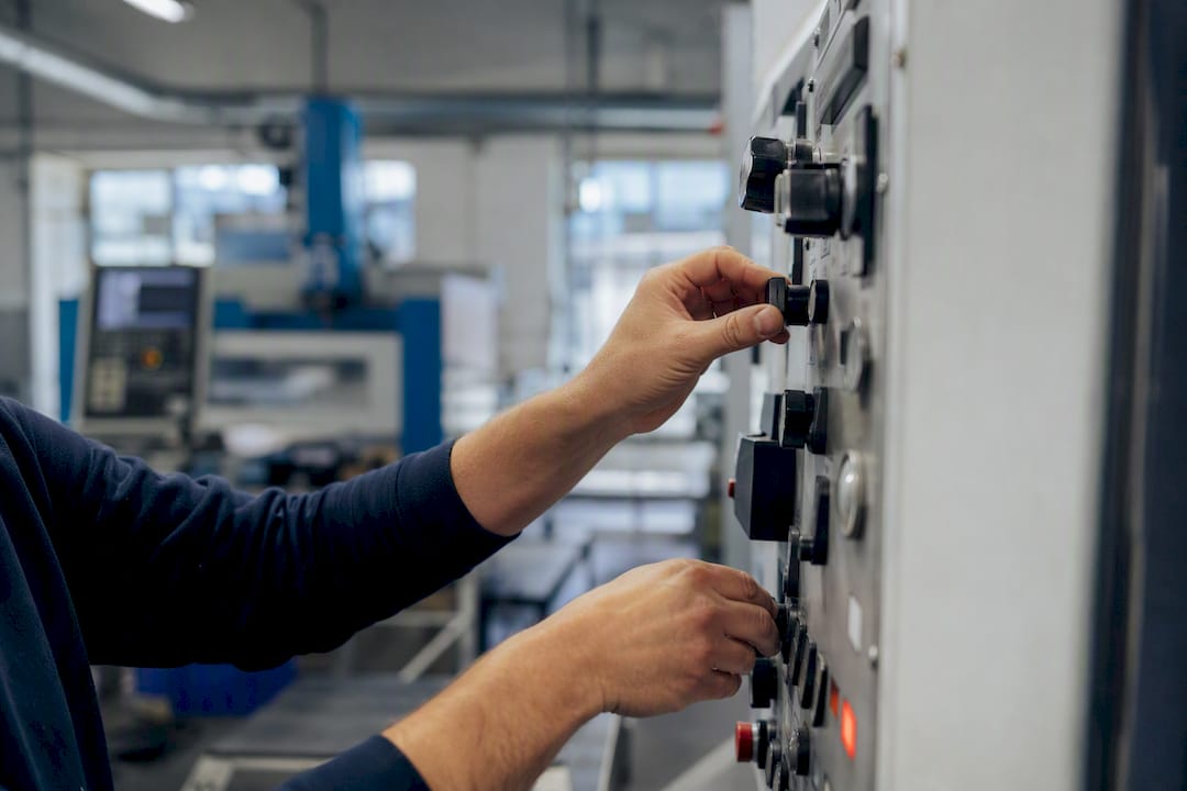 Hands operating industrial control panel manually