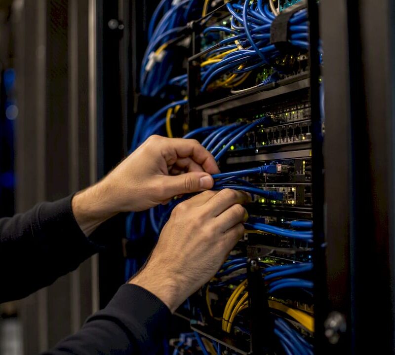 Technician connecting cable in server rack